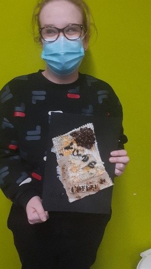 Student holding their mixed media coffee artwork
